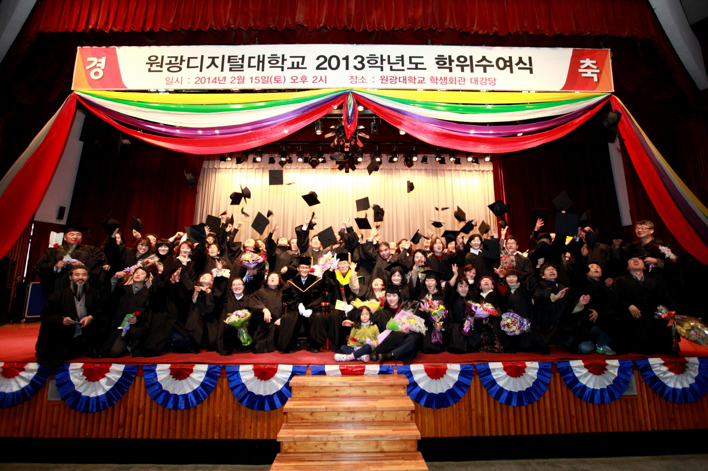 학위수여식에서 학생들이 단체로 모여 학사모를 던지고 있는 모습